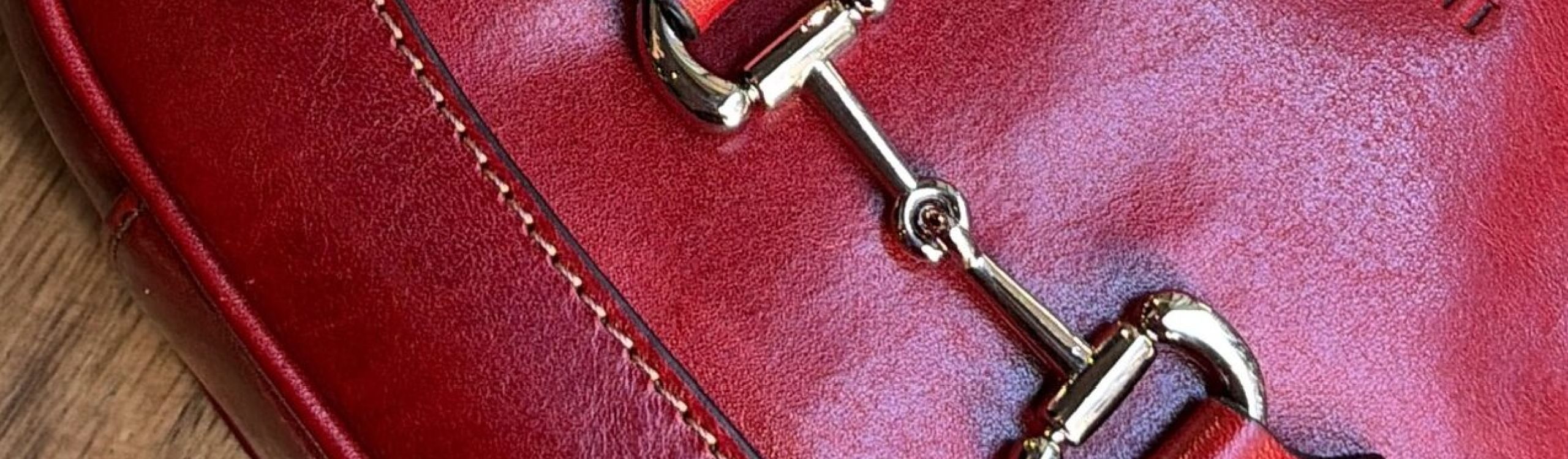 Close-up of a red Tornabuoni vegetable-tanned Italian leather bag showing hand stitching, burnished edges and the embossed Tornabuoni name
